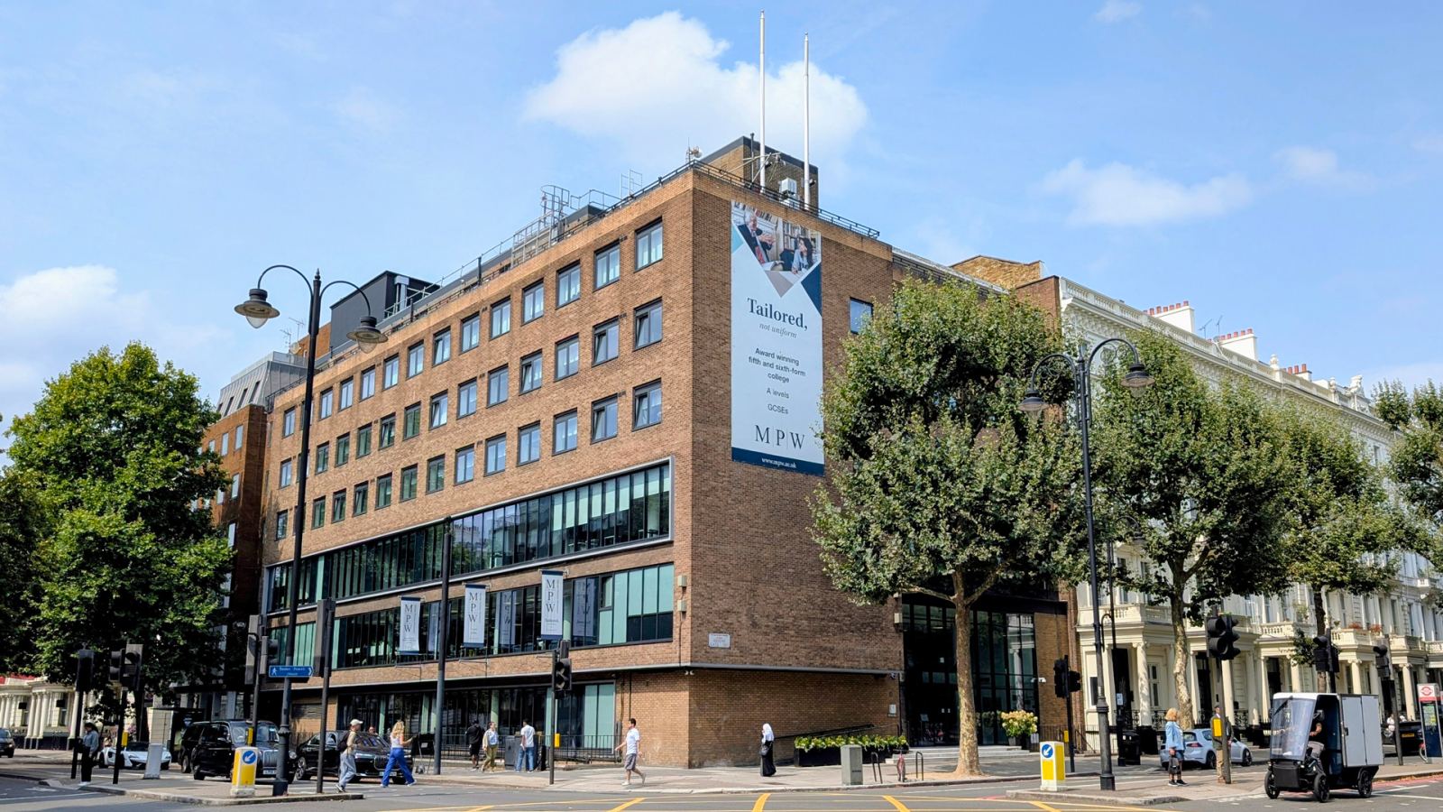 The brick frontage and college banner of MPW London on a tree-lined street